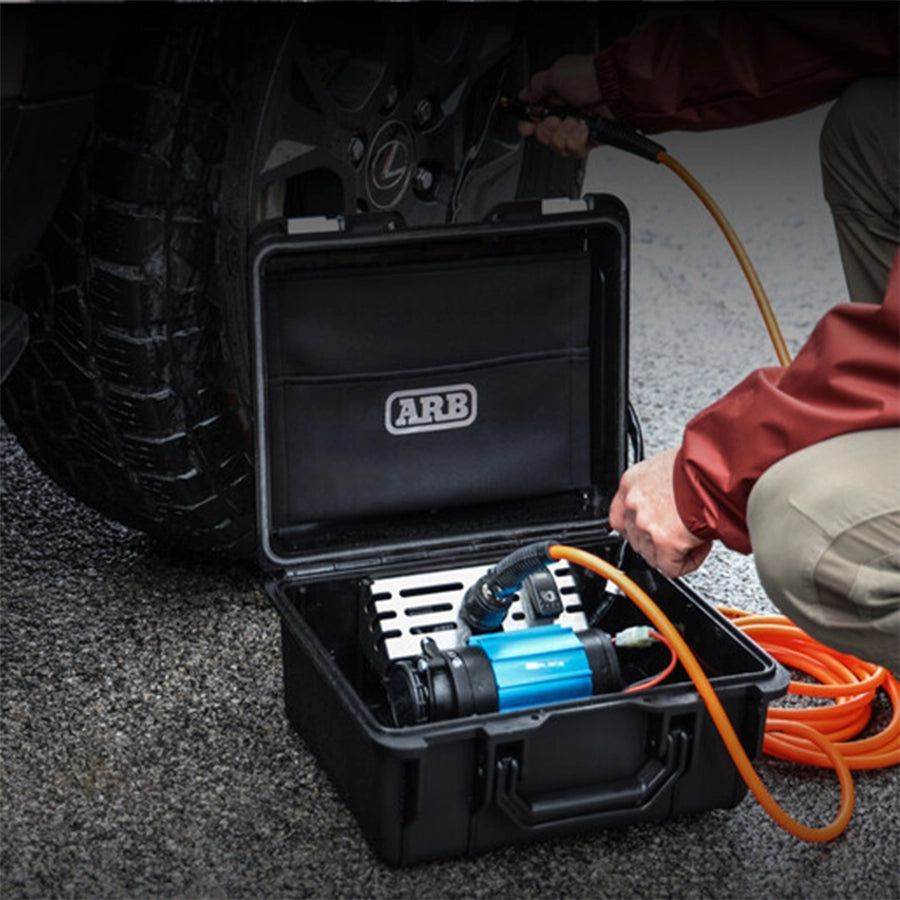 Black toolbox with ARB logo containing tools, open on a car floor.