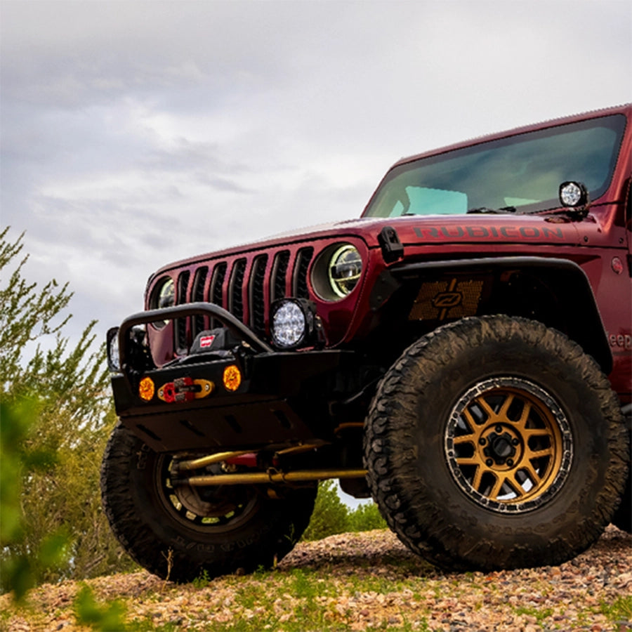 Red Jeep Wrangler with large off-road tires on a rocky terrain