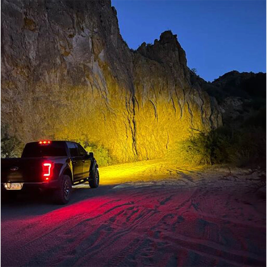 Truck with red lights on a dirt road at night in a rocky canyon