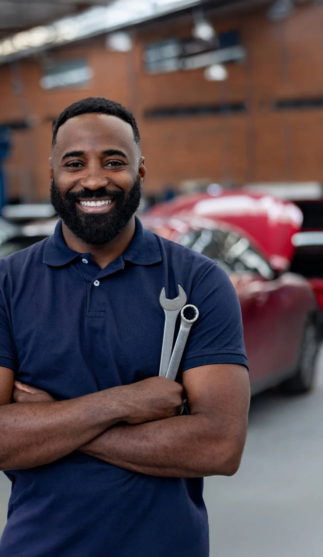 Man holding a wrench with a car in the background
